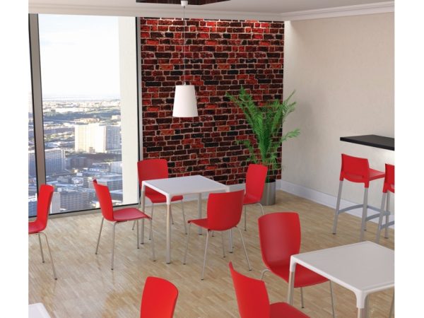 A modern dining area with red chairs and white tables. A large window offers a city view, and a brick accent wall adds character. A green plant is placed in one corner, and a white pendant light hangs from the ceiling.