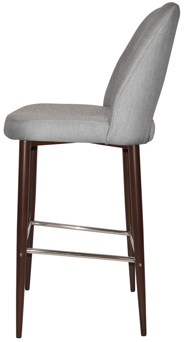 A side view of a modern bar stool with a padded, light gray upholstered seat and backrest. The stool has dark wooden legs and a metal footrest, giving it a sleek and contemporary design.