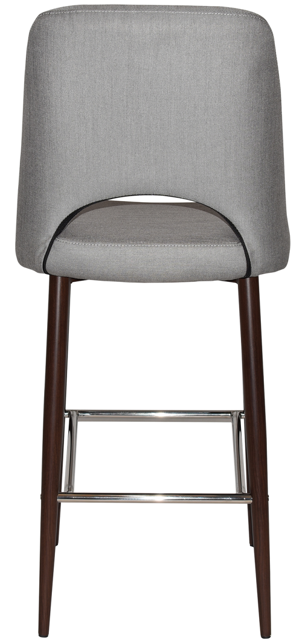 A gray upholstered bar stool with a curved backrest, featuring a cut-out section at the bottom. The stool stands on four dark wooden legs, supported by a chrome footrest. The design is modern and sleek, showing the back side of the chair.