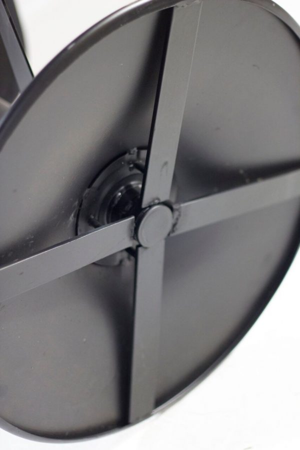 Close-up image of a black round wheel with a central hub and four spokes radiating outward. The wheel surface appears smooth and clean, and it is photographed against a neutral, light background.